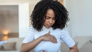 Junge Frau tastet ihre Brust ab