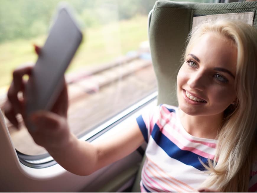 Eine Frau sitzt mit ihrem Smartphone in der Bahn