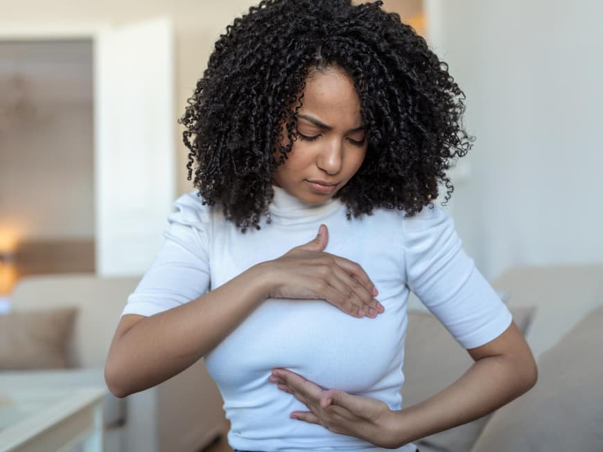 Junge Frau tastet ihre Brust ab