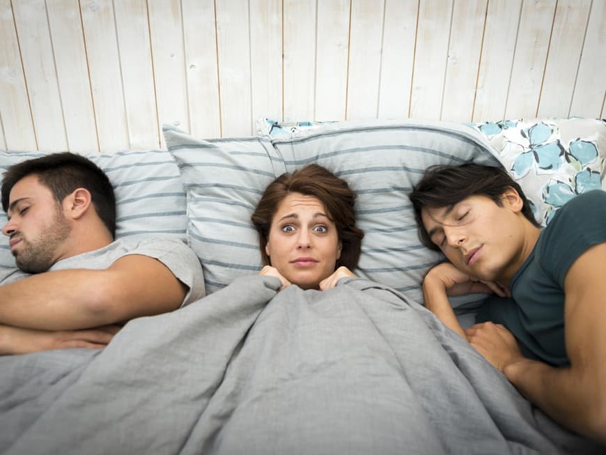 Ehemann oder Liebesaffäre? Frau im Bett mit zwei Männern