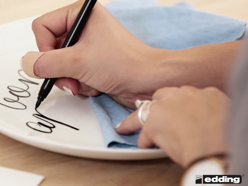 Die Handlettering-Expertin legt ein Mikrofaser-Tuch unter, damit die Schrift nicht versehentlich verwischt.