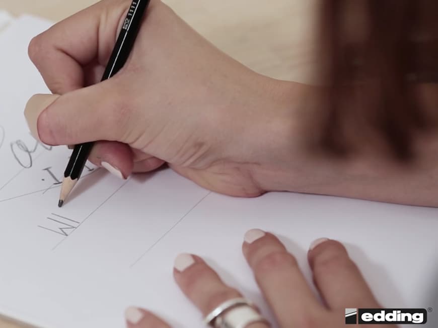 Dafür zeichnet die Handlettering-Expertin zunächst ihren Entwurf vor und überträgt ihn dann auf ihren gewünschten Untergrund.