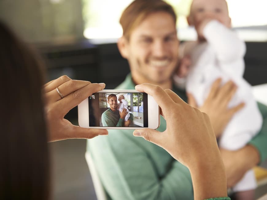 Frau fotografiert Partner und Baby