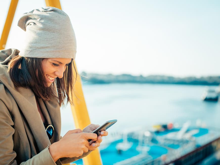 Frau freut sich über eine Nachricht auf ihrem Handy