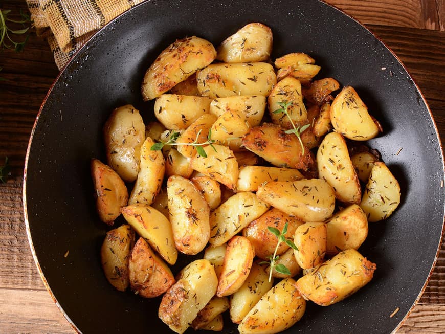 Mit Kräutern gewürzte Bratkartoffeln in einer großen Pfanne