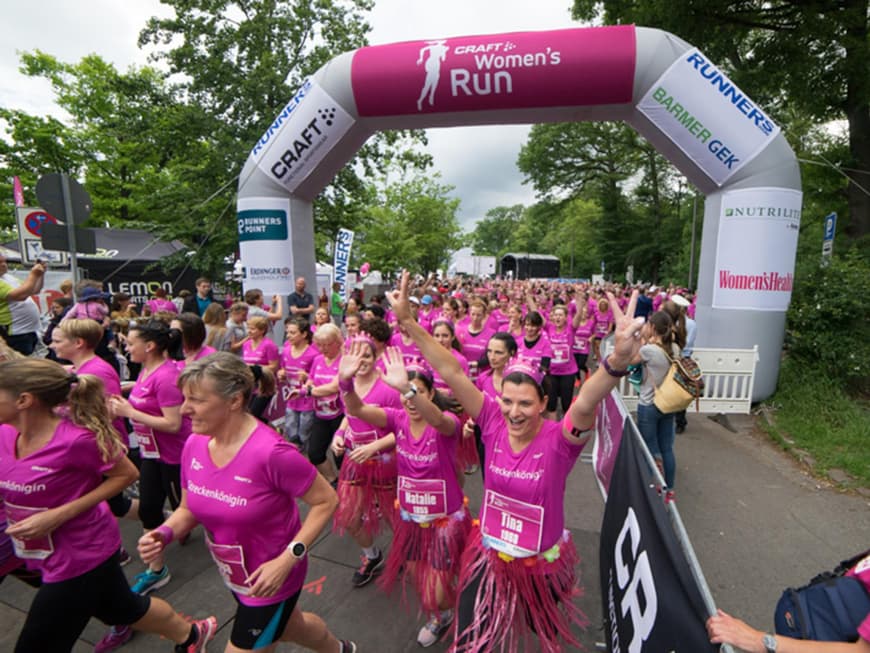 Viele Frauen in brombeerfarbenen Shirts laufen über die Zielgerade
