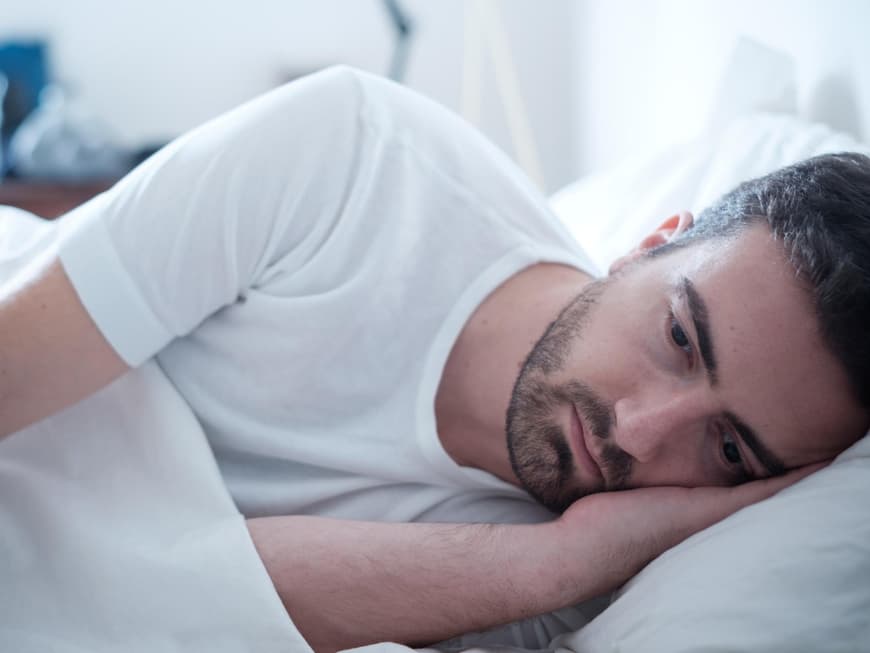 Deprimierter Mann liegt im Bett