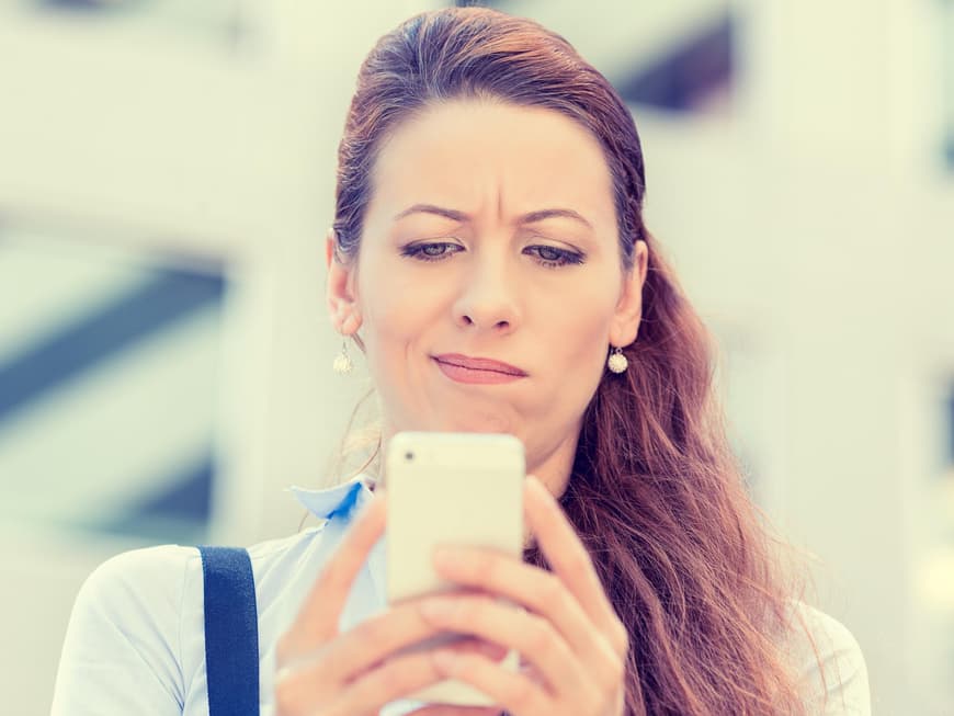 Frau schaut skeptisch auf ihr Handy