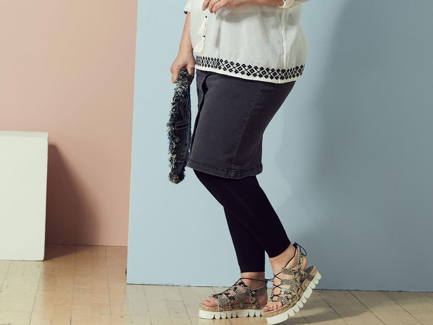 Anja in einer weißen Tunika mit Stickerei zum Jeansrock, Leggings und Turnschuhen
