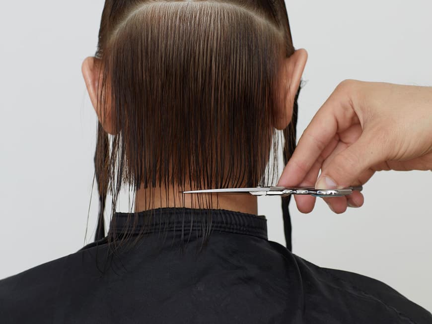 Der Friseur setzt die Schere in der Nackenpartie an