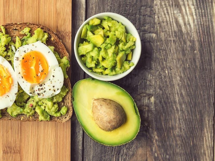 Scheibe Brot mit Avocado und gekochtem Ei auf Holzbrett