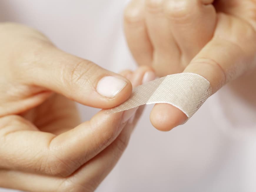 Ein Pflaster wird auf einen Zeigefinger geklebt