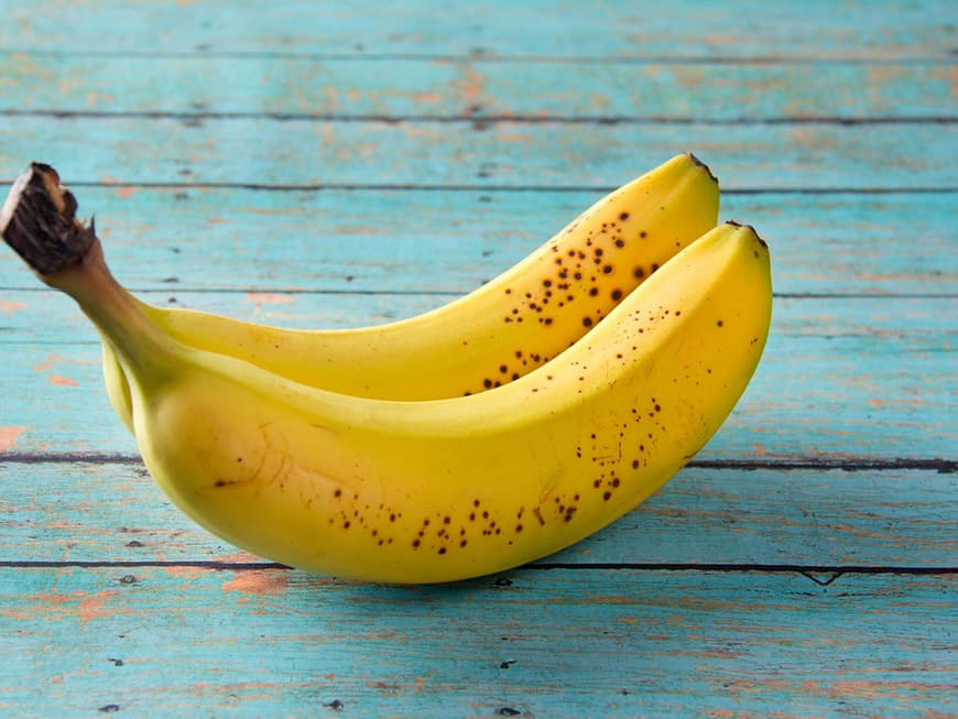 Zwei reife Bananen auf einem alten türkisfarbenen Holztisch