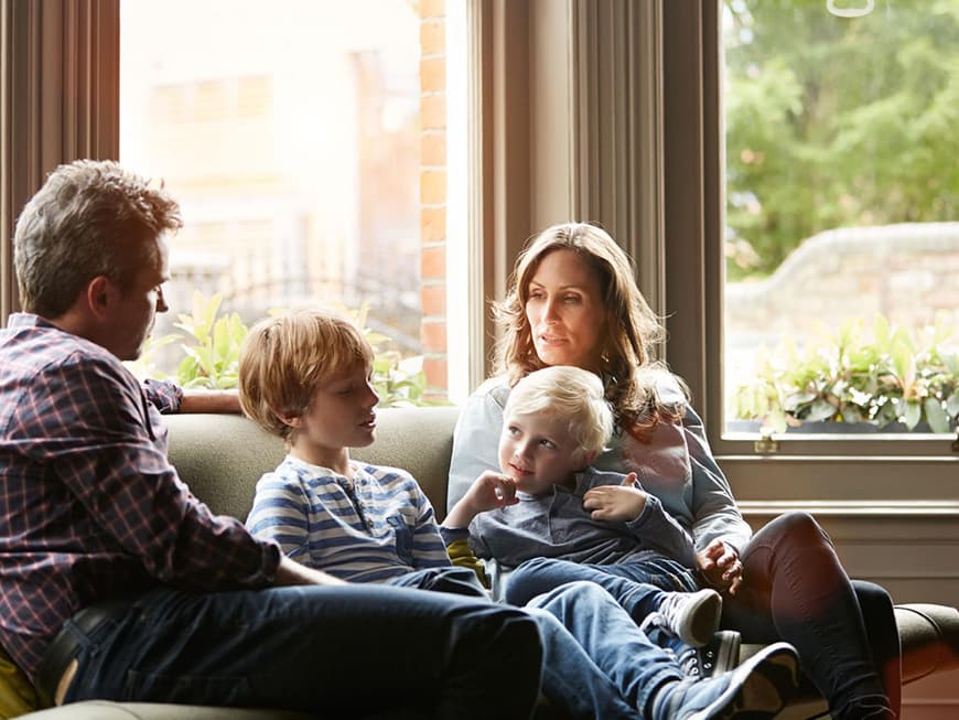 Zwei Jungs sitzen zwischen Vater und Mutter auf dem Sofa