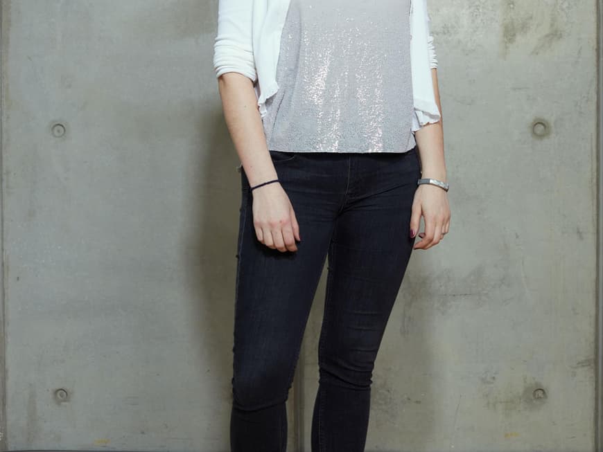 Daniela ungeschminkt in dunkler Jeans und Top zu weißer Strickjacke und Sneakers