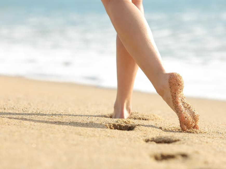 Frauenfüße hinterlassen Spuren am Sandstrand