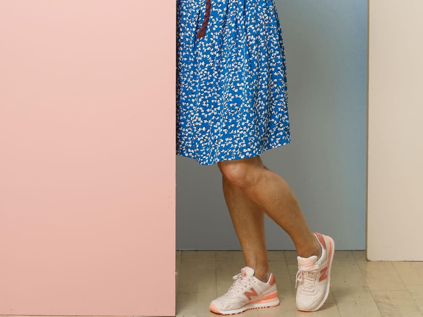 Andrea in einem blauen Kleid mit Blumenmuster zu hellen Turnschuhen