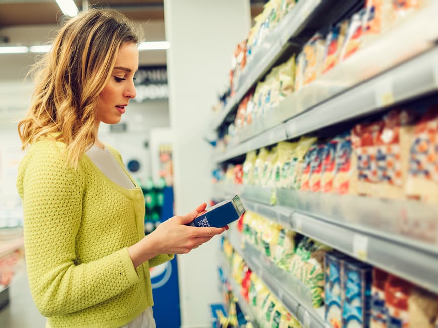 Frau liest im Supermarkt Zutaten auf Produktverpackung