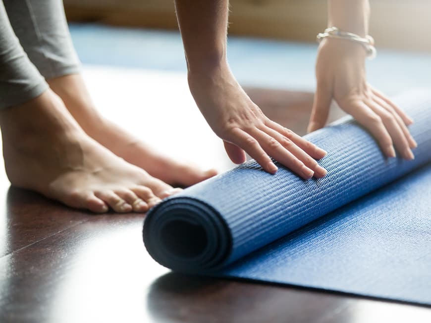 Frau rollt blaue Yoga-Matte aus