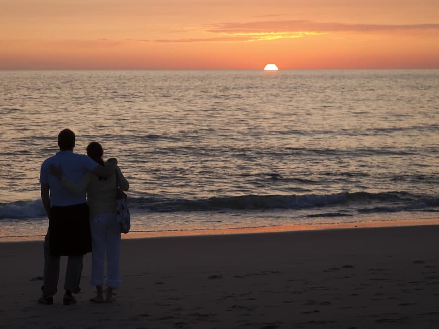 Paar steht umarmt am Strand im Sonnenuntergang