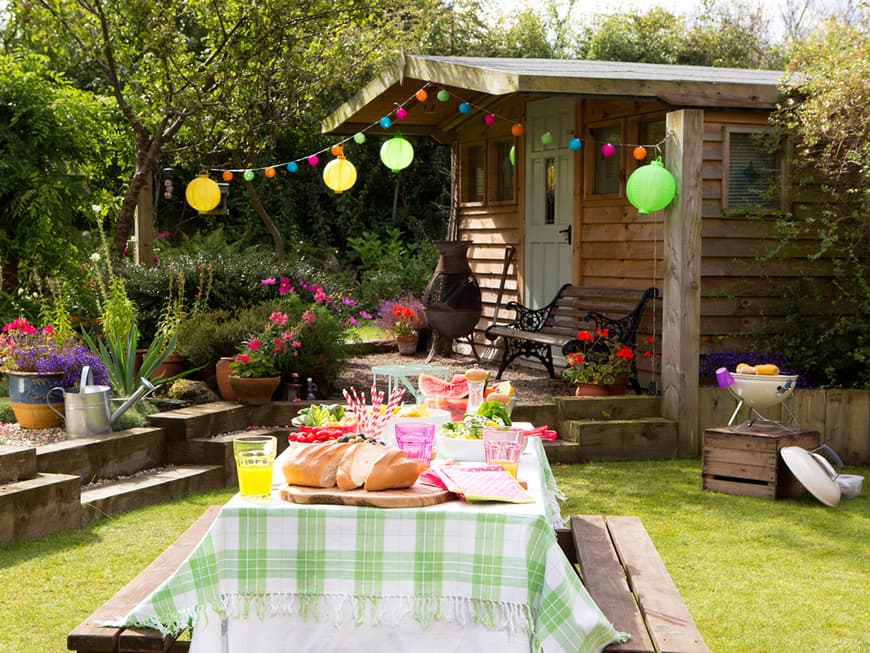 Garten mit Lampions und farbenfroh dekoriertem Tisch in der Mitte