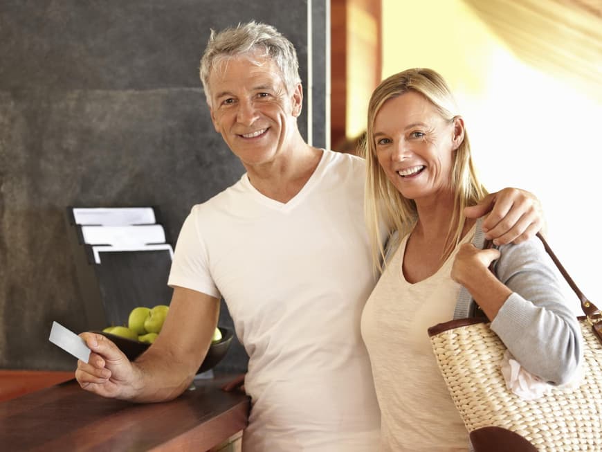Mann und Frau checken strahlend in ein Hotel ein