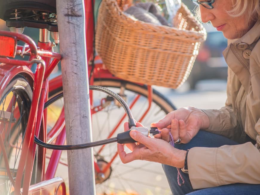 Frau mittleren Alters schließt ihr Fahrrad ab