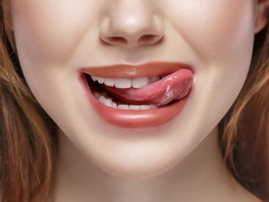 Frau streckt Zunge raus und leckt sich die Lippen