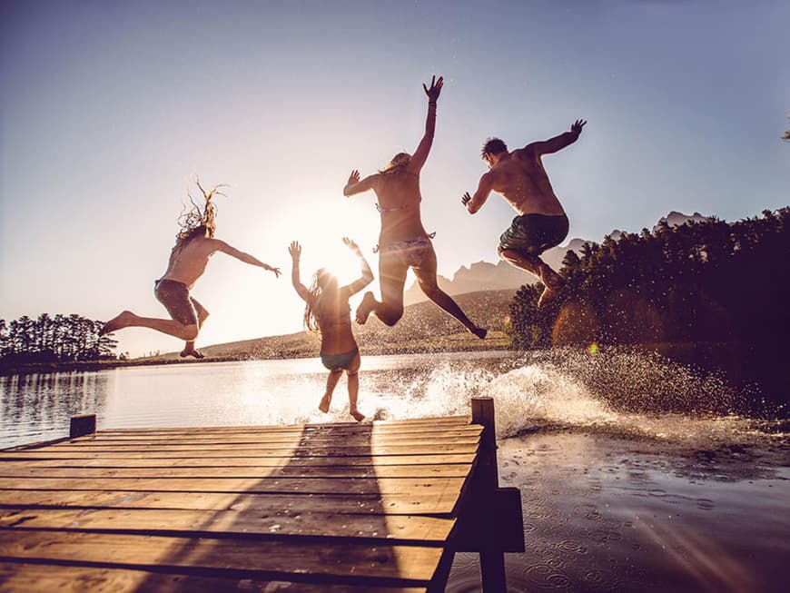 Gruppe von Menschen, die vom Steg ins Wasser springt.