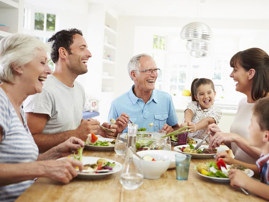 Glückliche Familie isst am Tisch zusammen