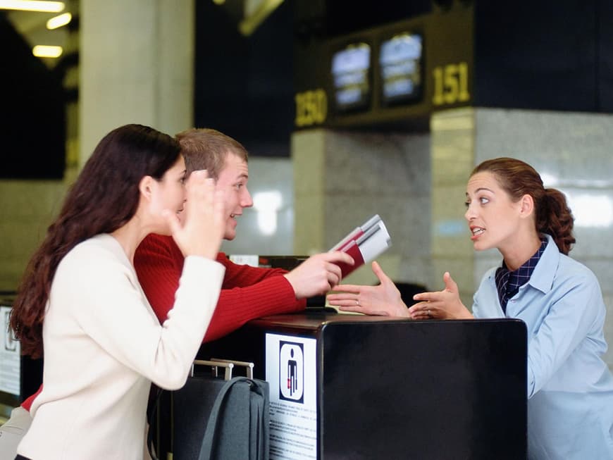 Paar diskutiert mit Bodenpersonal am Flughafen