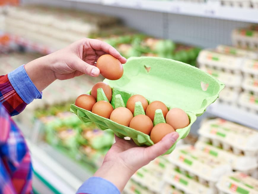 Zwei Hände mit Eierkarton im Supermarkt