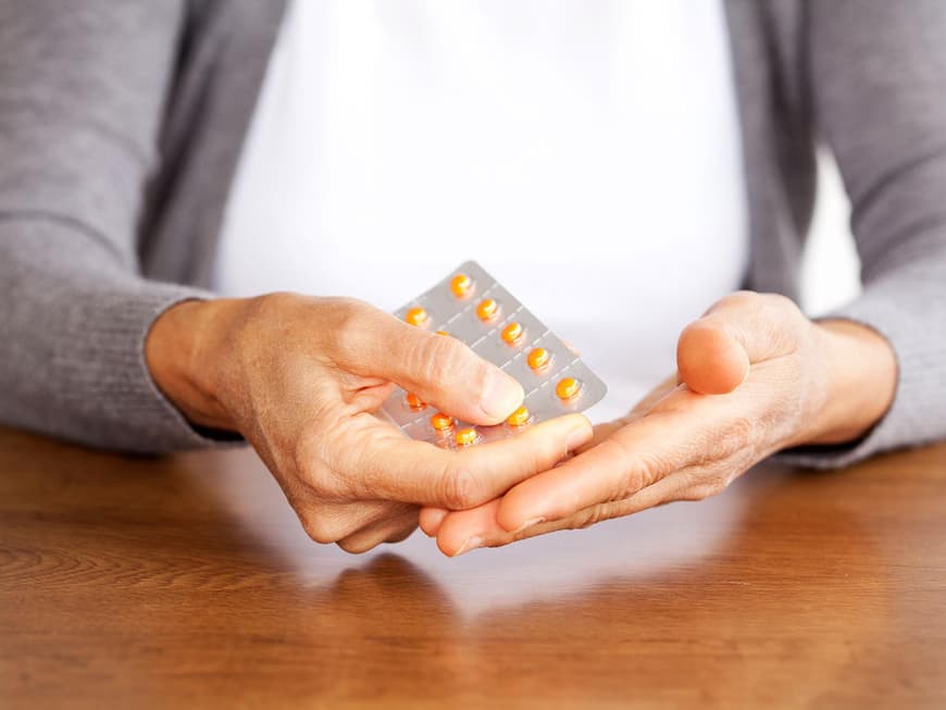 Hände einer reiferen Frau mit Tabletten