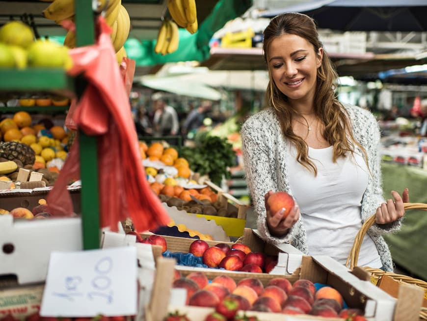 Lächelnde Frau an einem Marktstand mit Pfirsichen