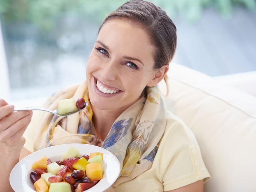 Hübsche Frau isst lächelnd Obstsalat