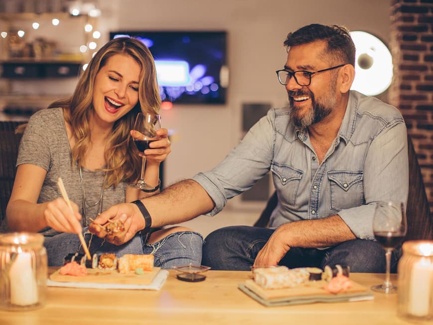 Paar isst gemeinsam Sushi und trinkt Rotwein