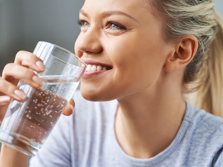 Junge, blonde Frau trink ein Glas Wasser
