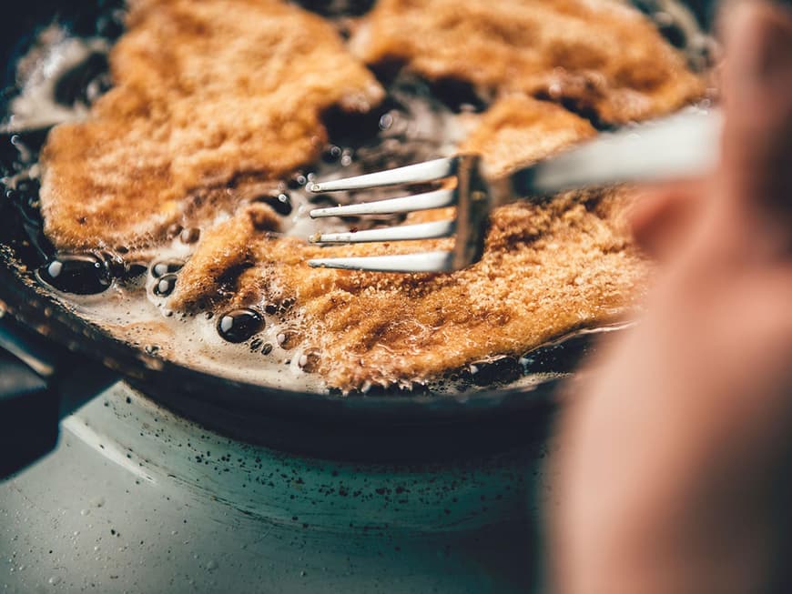 Panierte Schnitzel in einer Pfanne mit Fett