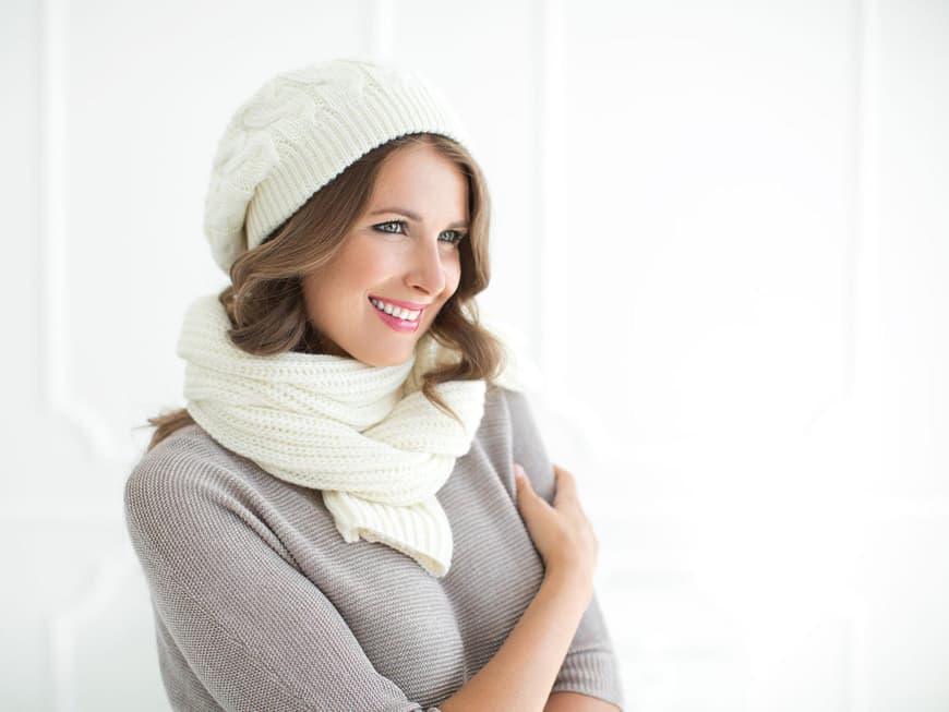 Lächelnde Frau in Strickpullover, Schal und Mütze
