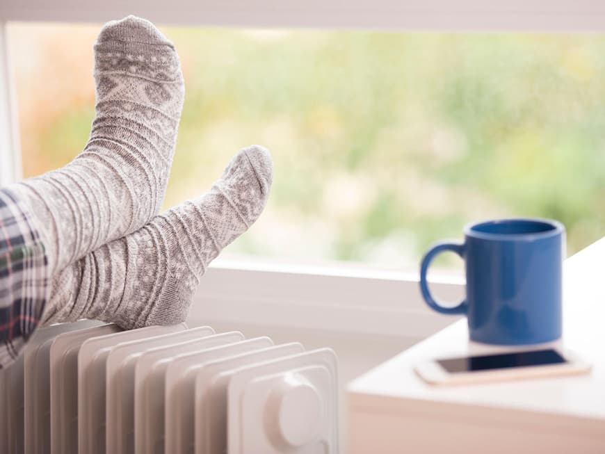 Füße mit winterlichen Socken auf Heizung