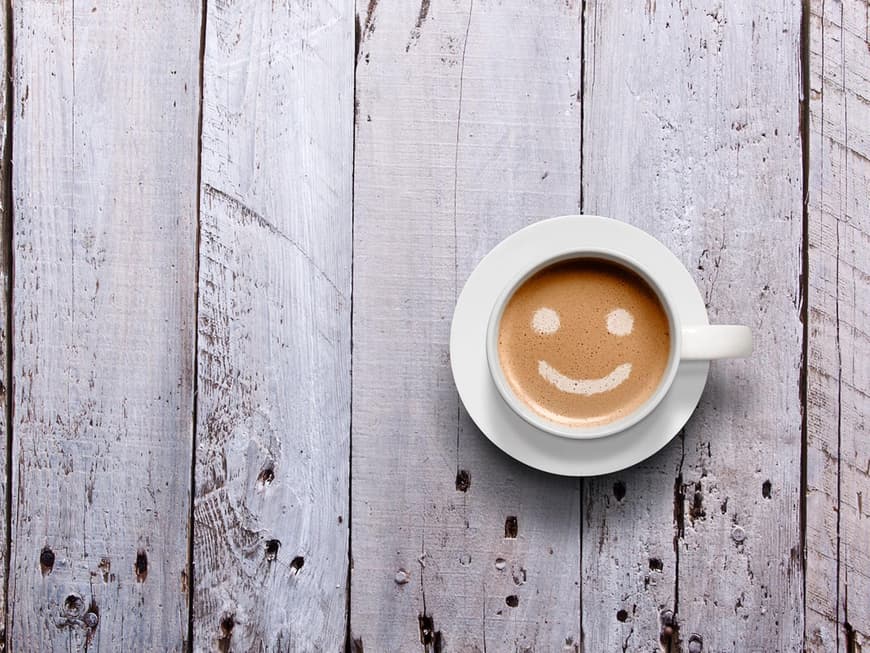 Tasse Kaffee mit lächelndem Gesicht im Schaum