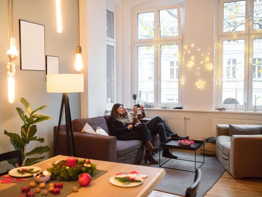 Paar sitzt auf dem Sofa im Wohnzimmer mit mehreren indirekten Lichtquellen
