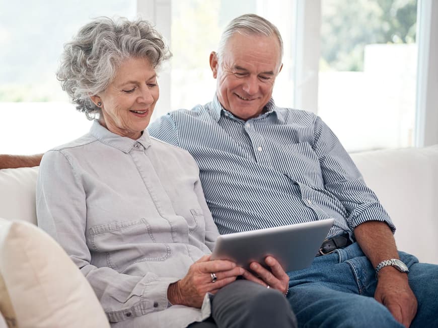 Älteres Paar mit Tablet auf dem Sofa 