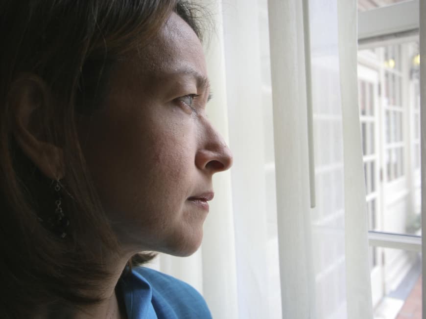 Frau blickt nachdenklich aus dem Fenster