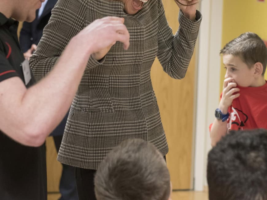 Meghan Markle in einem karierten Jäckchen mit Kindern in einem Gemeinschafts- und Freizeitzentrum in Wales