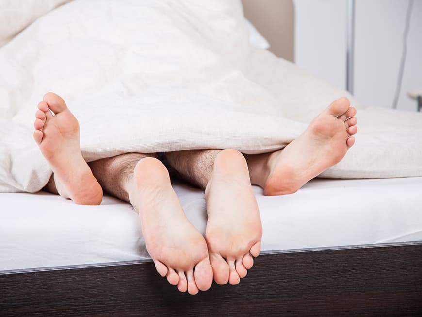 Füße von einem Paar beim Sex unter der Decke