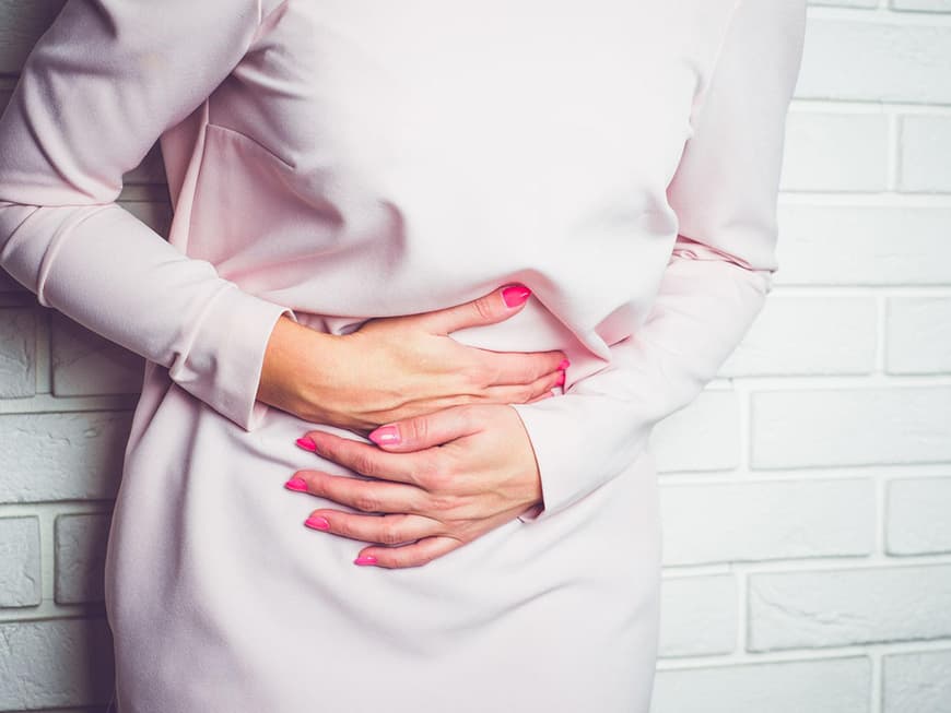 Frau hält sich den Bauch vor Blähungen