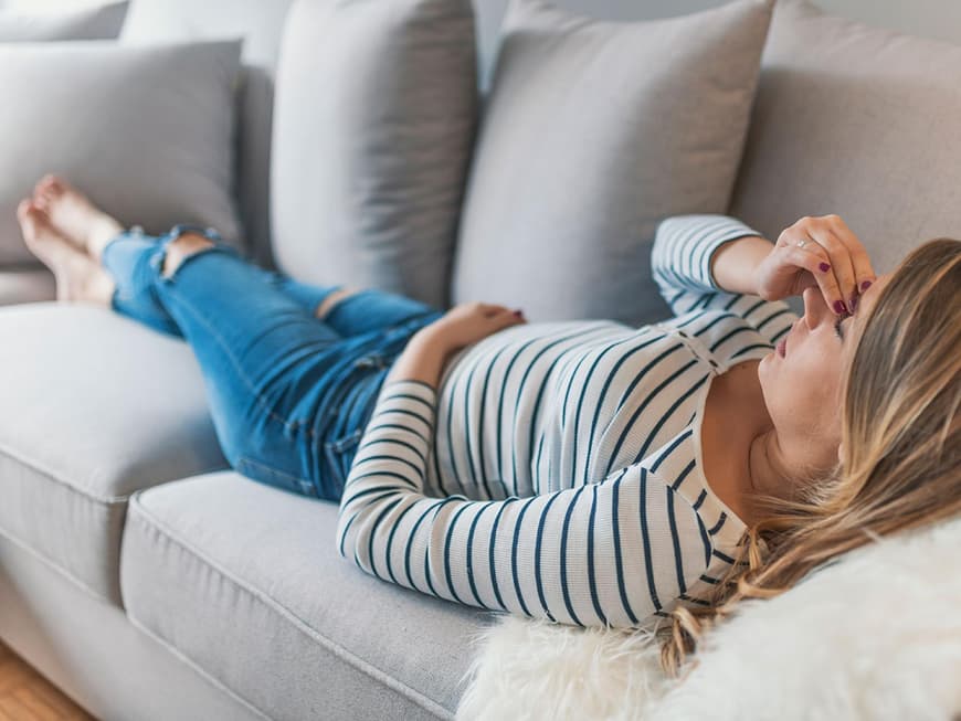 Frau mit Kreislaufproblemen auf dem Sofa