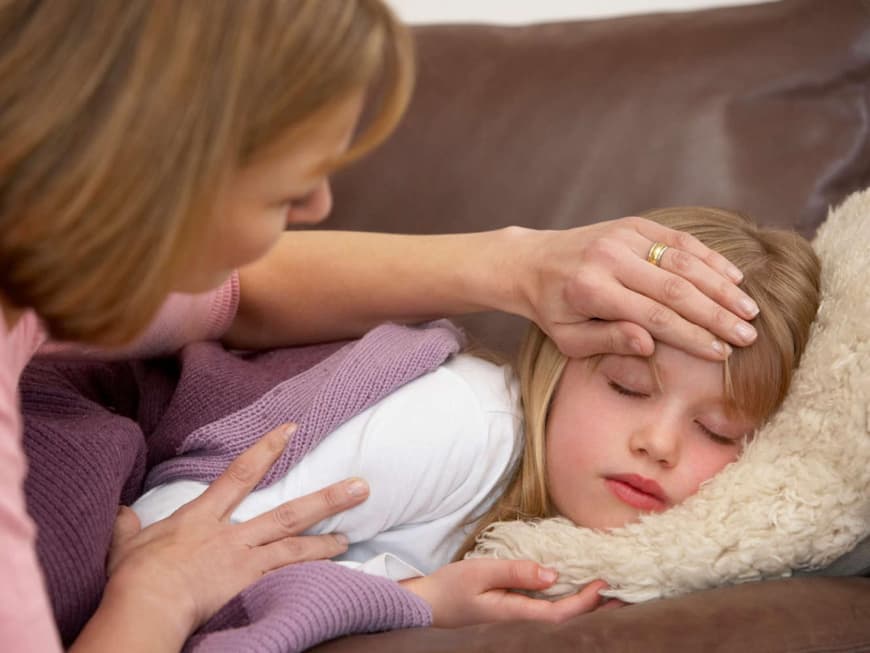 Fieber: Mutter fühlt mit der Hand die Temperatur auf der Stirn ihrer Tochter