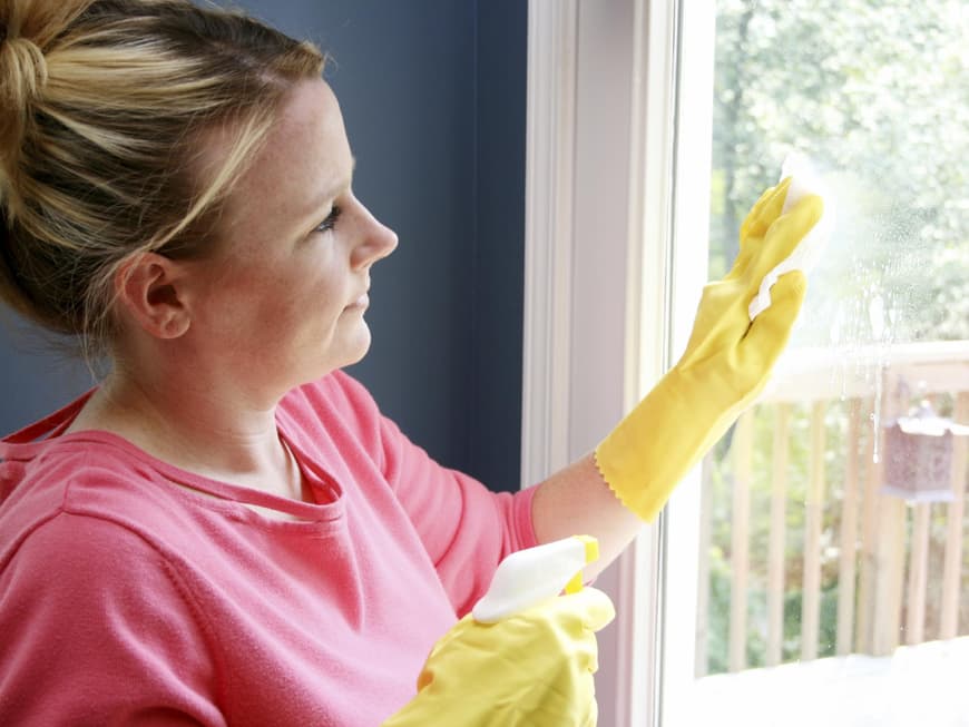 Frau putzt Fenster